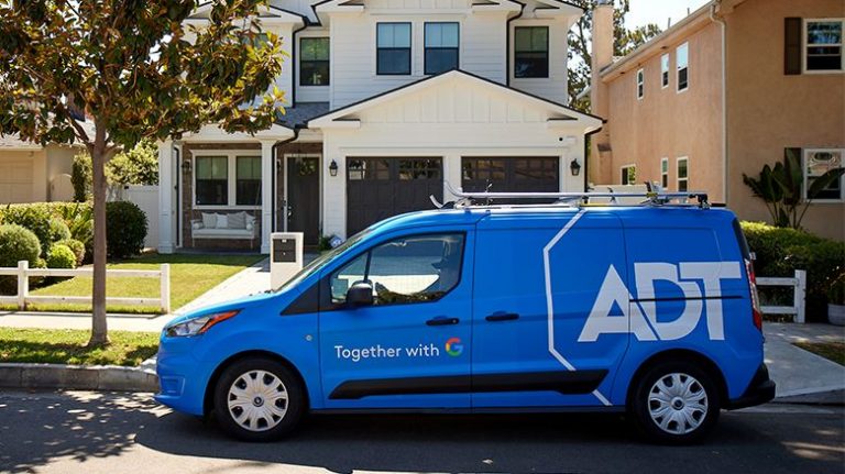 A blue ADT security installation van parked in front of a white residential house.